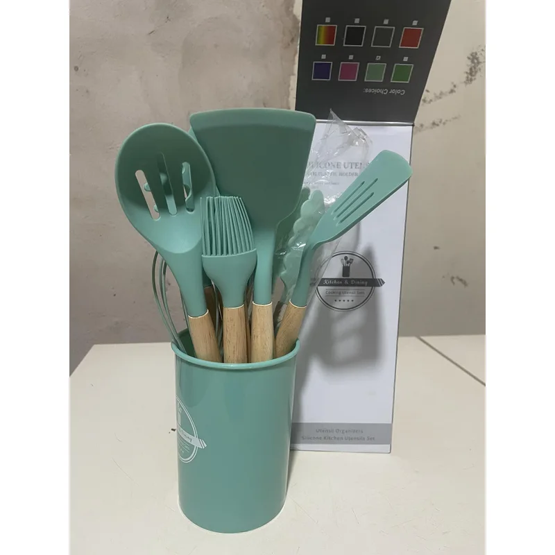 Set de utensilios de cocina de silicona verde con mango de madera en su recipiente